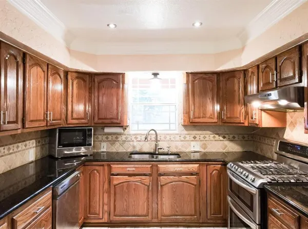 a kitchen with stainless steel appliances granite countertop a stove a sink and a microwave