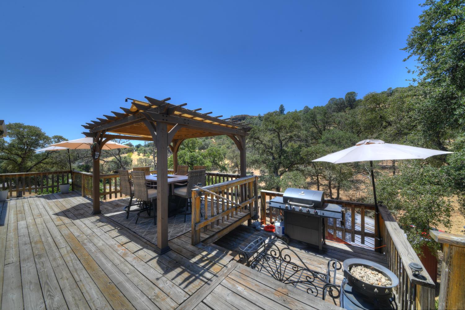 17045 Table Mountain Road Jamestown, CA 95327 - Photo 38 of 59 a view of a roof deck with table and chairs under an umbrella with wooden floor