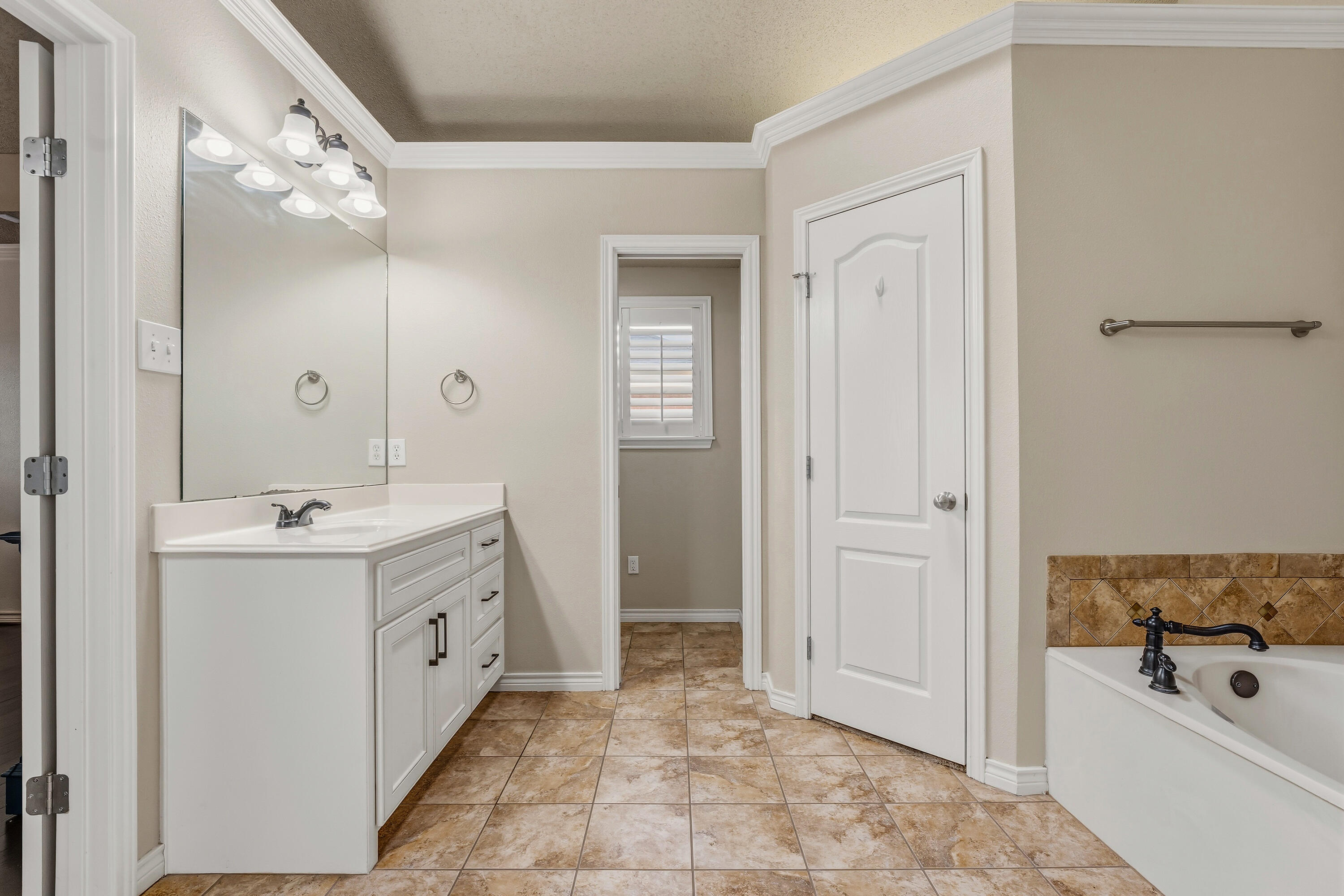 6903 87th Street Lubbock, TX 79424 - Photo 17 of 35 a bathroom with a tub a sink and mirror