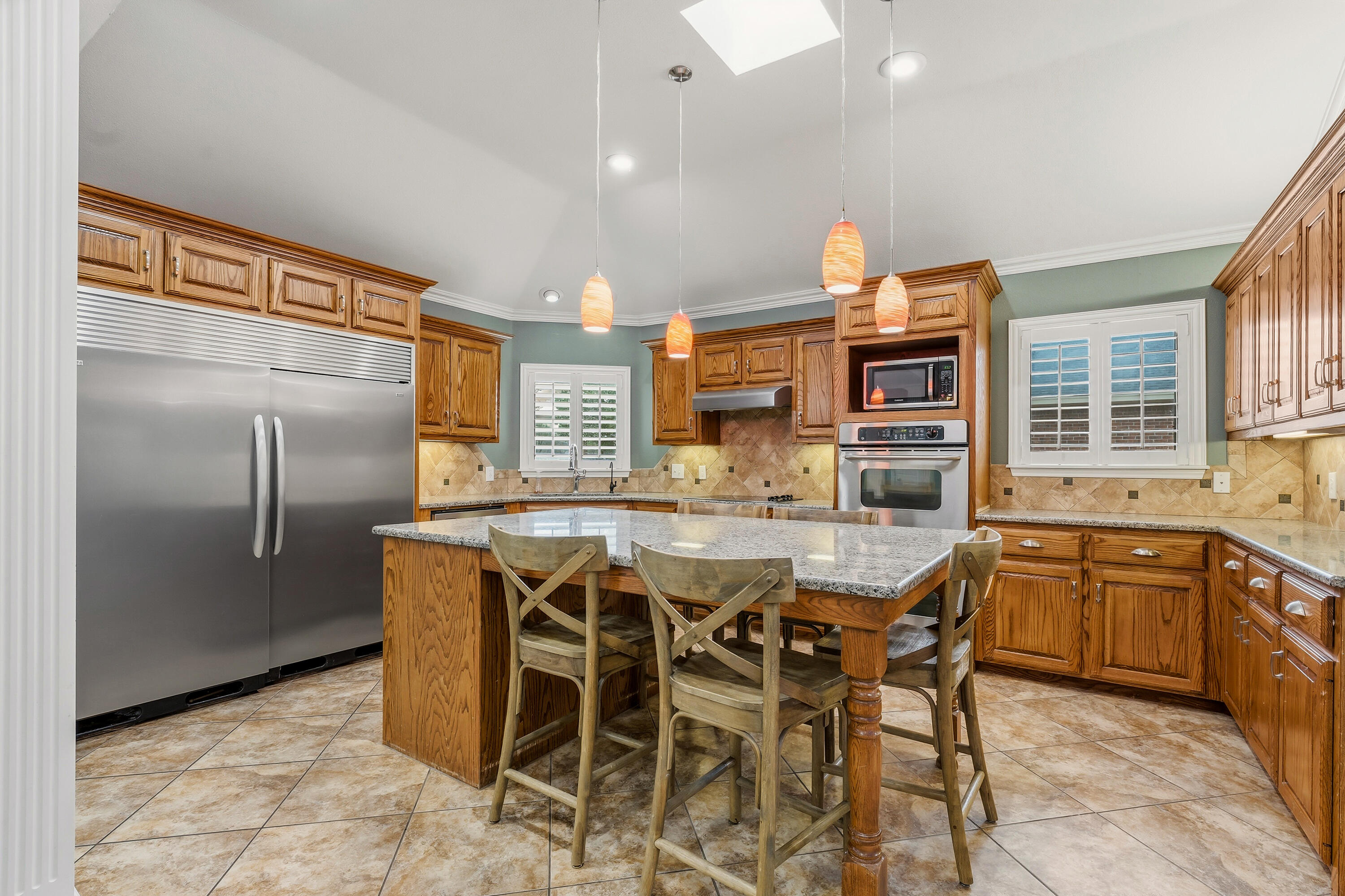 6903 87th Street Lubbock, TX 79424 - Photo 9 of 35 a kitchen with stainless steel appliances kitchen island granite countertop a table chairs and a refrigerator