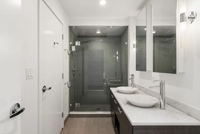 a bathroom with a double vanity sink mirror and shower