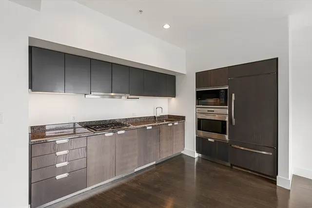 a kitchen with granite countertop a refrigerator and a stove top oven