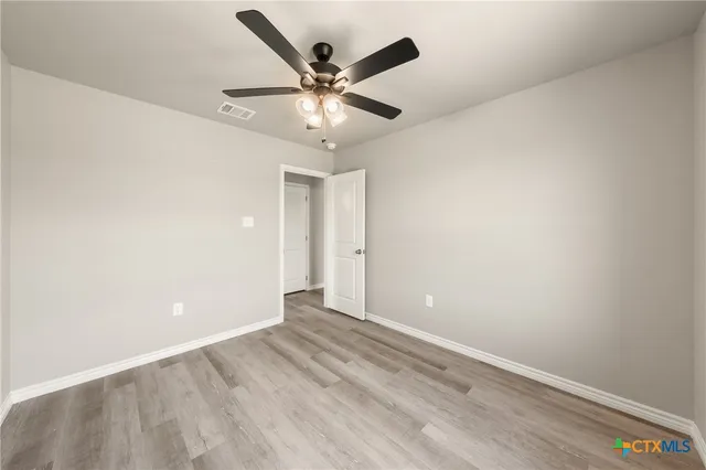 an empty room with a window and a fan