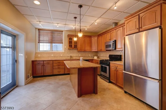 a kitchen with stainless steel appliances granite countertop a refrigerator a sink a stove and a refrigerator