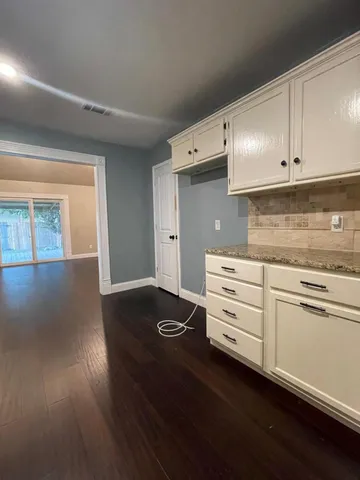a kitchen with granite countertop white cabinets and wooden floor