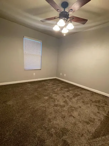 an empty room with a chandelier fan and windows