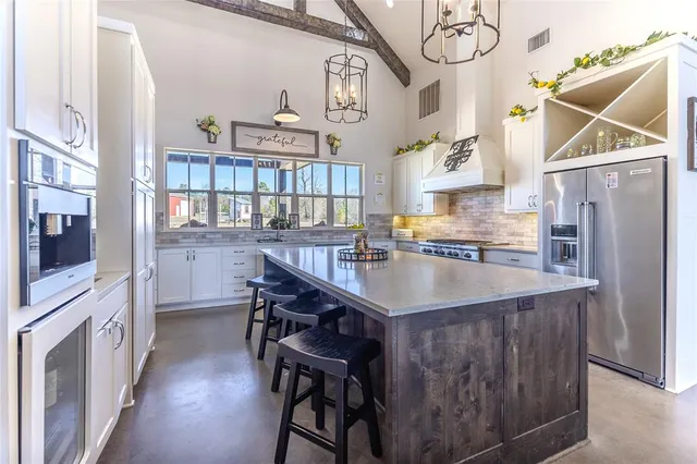 a kitchen with stainless steel appliances granite countertop a refrigerator a stove and a wooden floor