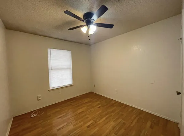 an empty room with wooden floor and fan