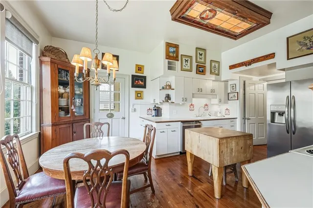 a large white kitchen with stainless steel appliances granite countertop a stove a sink dishwasher a dining table and chairs with wooden floor