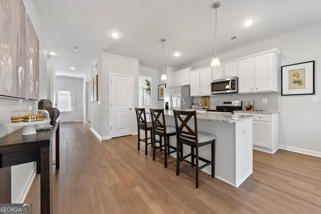 a kitchen with kitchen island wooden floors appliances and white cabinets