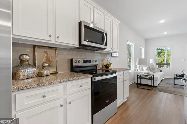 a kitchen with stainless steel appliances granite countertop a stove a sink dishwasher and microwave with wooden floor