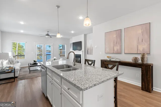 a kitchen with granite countertop stainless steel appliances a sink stove and wooden floor