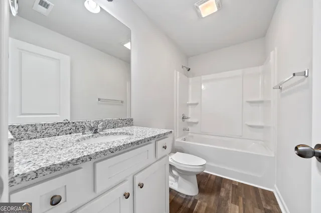 a bathroom with a granite countertop sink a toilet and bathtub