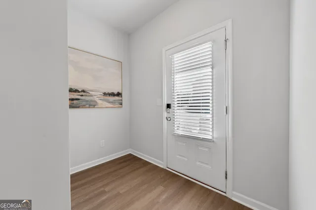 a view of an empty room with wooden floor and a window