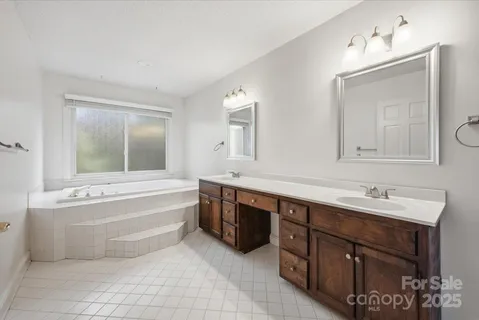 a spacious bathroom with a tub sink and mirror