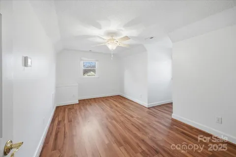 an empty room with wooden floor and a ceiling fan
