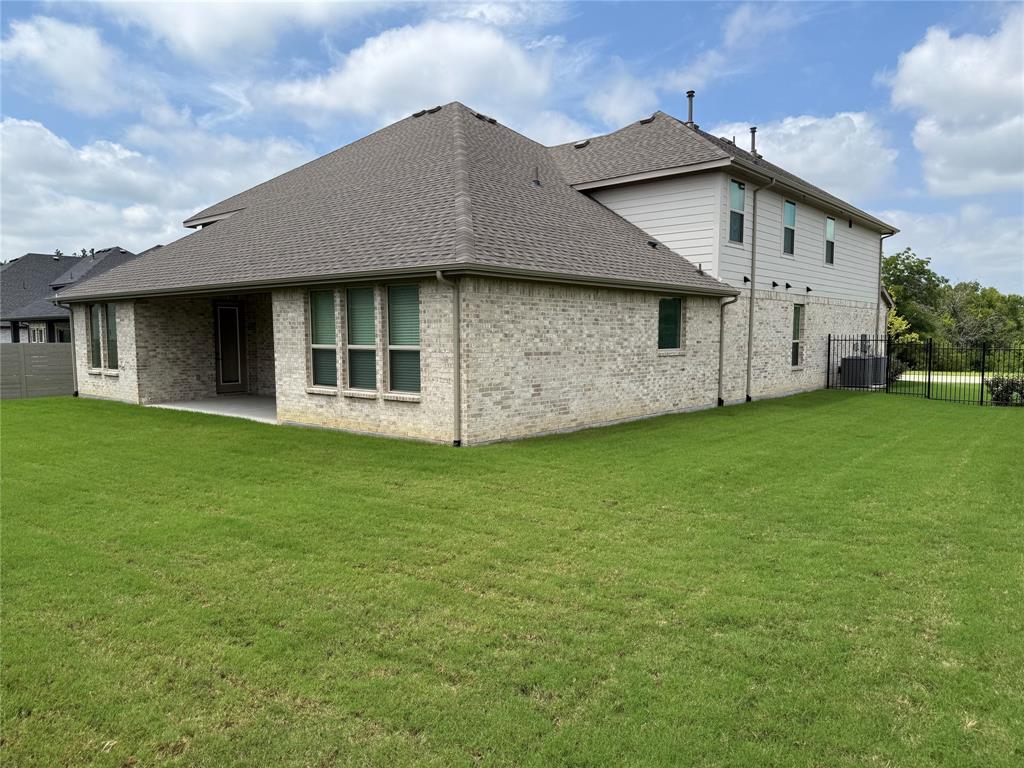 2708 Andesite Road McKinney, TX 75071 - Photo 5 of 35 Spacious rear yard with a covered patio, brick and siding exterior, multiple windows, and a black wrought iron fence