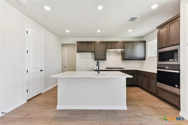 a kitchen with stainless steel appliances granite countertop a sink a stove a refrigerator and cabinets