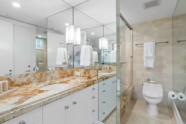 a bathroom with a granite countertop sink a toilet and a shower