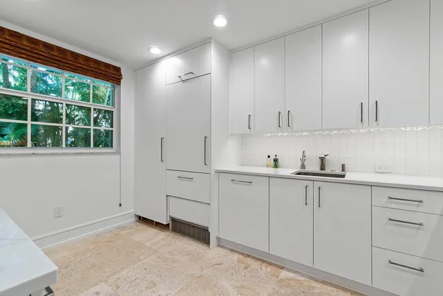 a kitchen with white cabinets and window