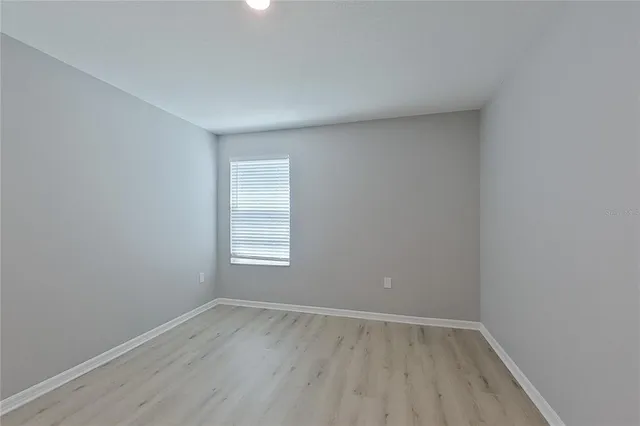 an empty room with wooden floor and window