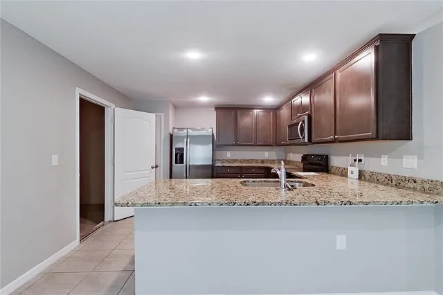 a large kitchen with granite countertop a sink and a refrigerator