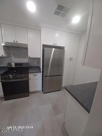 a kitchen with granite countertop white cabinets and stainless steel appliances