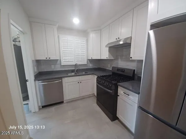 a kitchen with stainless steel appliances granite countertop a sink stove refrigerator and cabinets