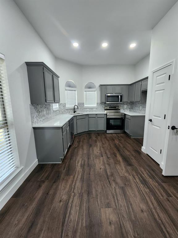 533 Bowie Street Forney, TX 75126 - Photo 4 of 7 a kitchen with kitchen island granite countertop wooden floors and stainless steel appliances