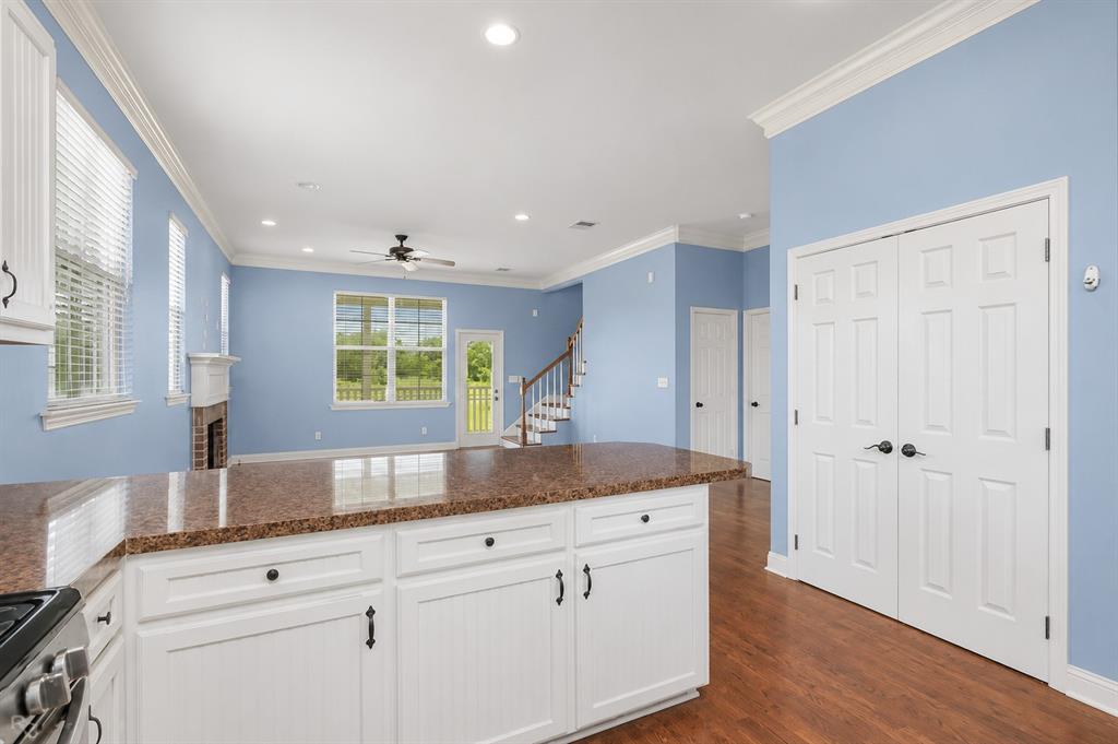 179 Ranchtown Road Elm Grove, LA 71051 - Photo 6 of 26 Kitchen island with a speckled countertop and white base cabinetry, featuring recessed lighting, wood-finish flooring, a double-door closet, and a visible staircase