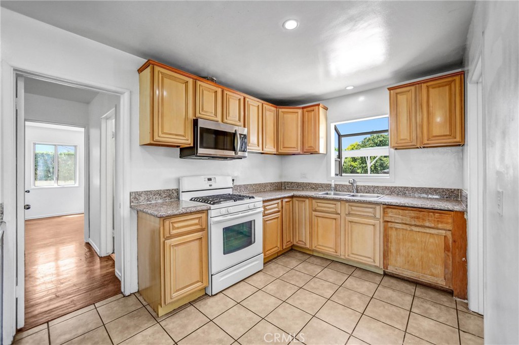 6225 Langdon Avenue Van Nuys, CA 91411 - Photo 5 of 15 a kitchen with stainless steel appliances granite countertop a stove top oven a sink dishwasher and a refrigerator with wooden cabinets