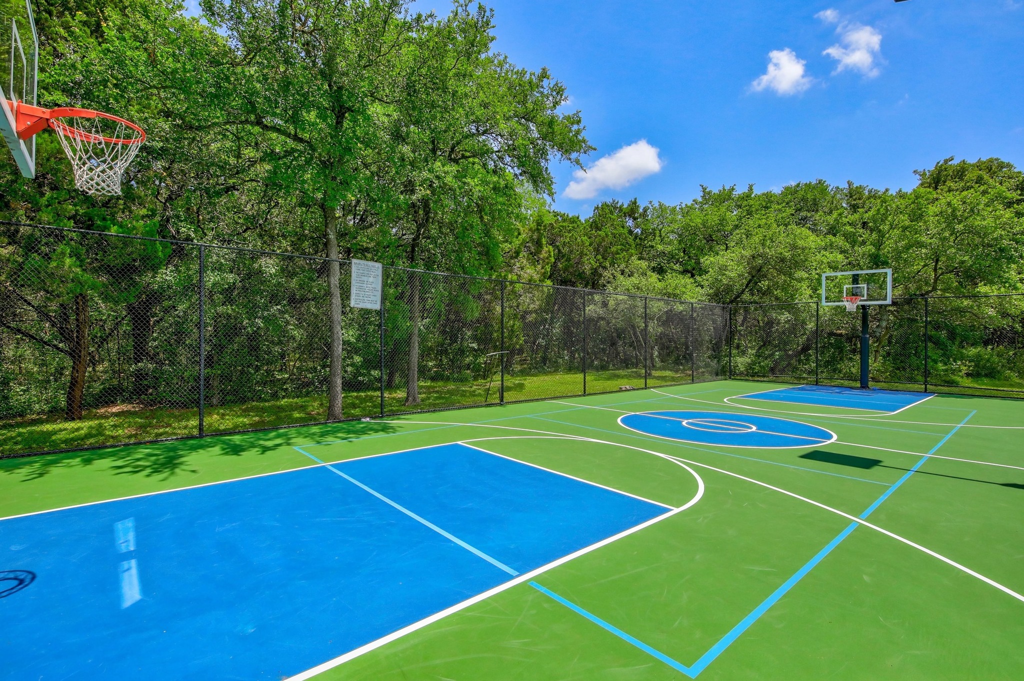 7705 Jester Boulevard Austin, TX 78730 - Photo 33 of 36 An outdoor court for recreation, fenced in and surrounded by lush green trees.