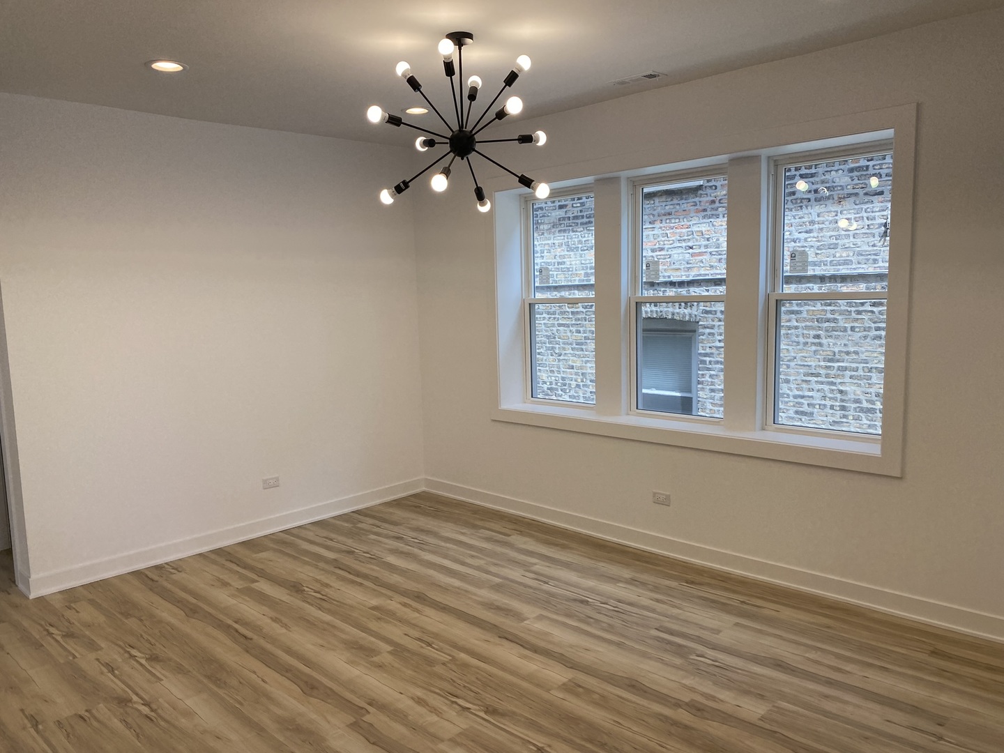 4352 West Augusta Boulevard, Unit 1 Chicago, IL 60651 - Photo 5 of 16 a view of an empty room with a window and wooden floor