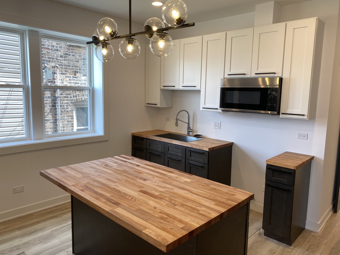 4352 West Augusta Boulevard, Unit 1 Chicago, IL 60651 - Photo 6 of 16 a kitchen with stainless steel appliances kitchen island granite countertop a sink a stove and microwave