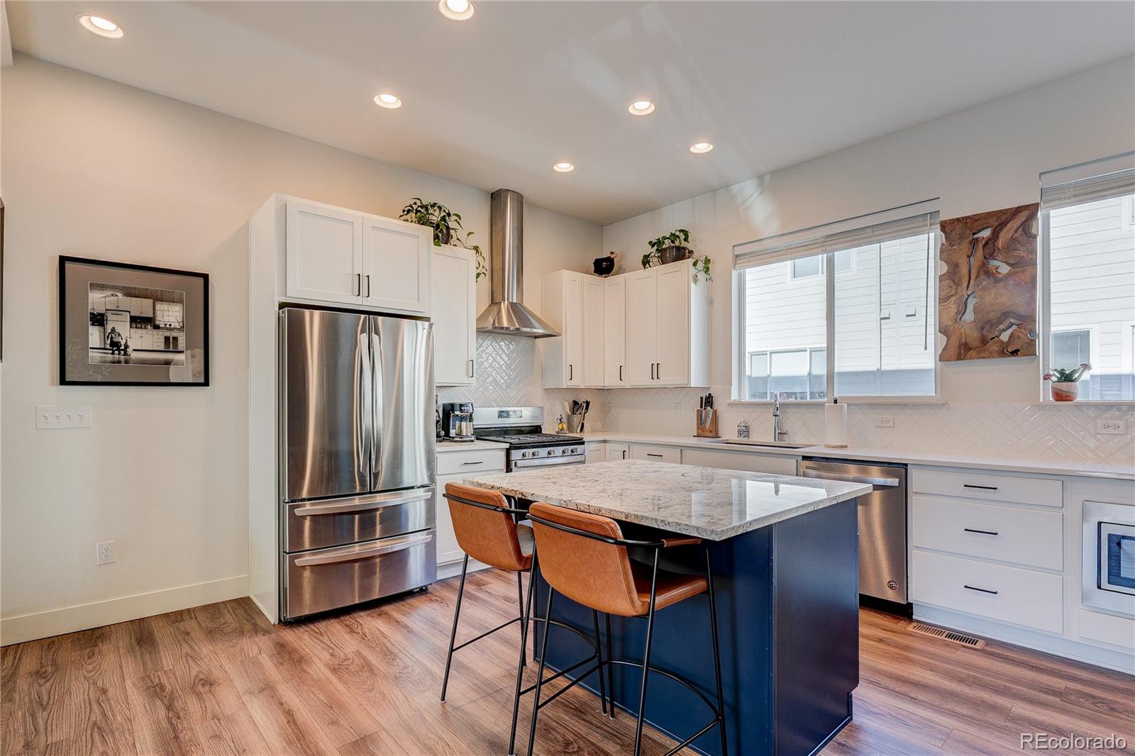 7825 West 42nd Avenue Wheat Ridge, CO 80033 - Photo 5 of 35 a kitchen with granite countertop a table chairs refrigerator and wooden cabinets