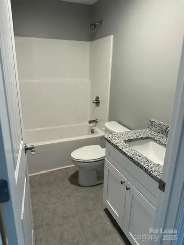 a bathroom with a granite countertop sink a toilet and shower