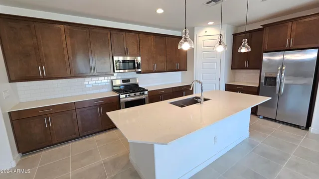 a kitchen with stainless steel appliances a sink a stove a refrigerator and cabinets