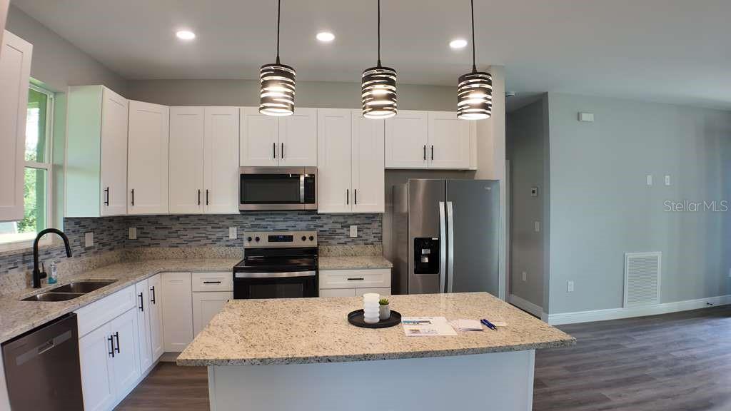4200 Leaf Road Sebring, FL 33875 - Photo 4 of 9 a kitchen with kitchen island granite countertop a sink a counter top space appliances and cabinets