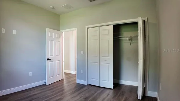 an empty room with wooden floor & closet area