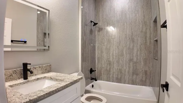a bathroom with a granite countertop sink and a mirror