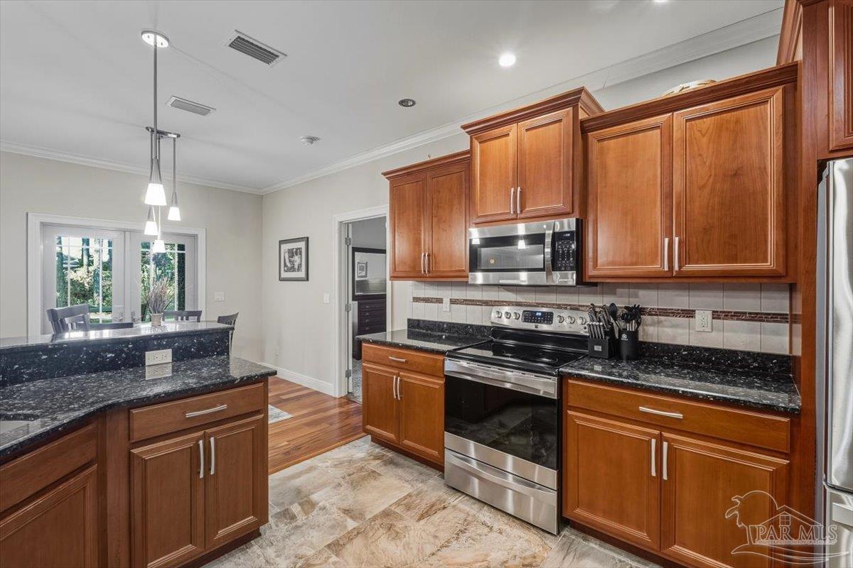 8756 Olivera Street Navarre, FL 32566 - Photo 17 of 41 a kitchen with stainless steel appliances granite countertop wooden cabinets and a stove top oven