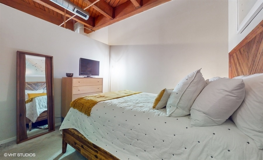 1040 West Adams Street, Unit 347 Chicago, IL 60607 - Photo 17 of 29 a bedroom with a bed and a mirror
