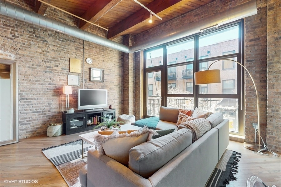 1040 West Adams Street, Unit 347 Chicago, IL 60607 - Photo 4 of 29 a living room with furniture a flat screen tv and a floor to ceiling window