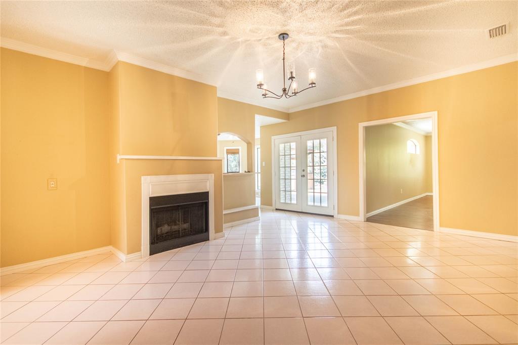 308 Sanders Road Denton, TX 76210 - Photo 12 of 31 Tile flooring, crown molding, double French doors, fireplace with mantel, and a multi-arm chandelier