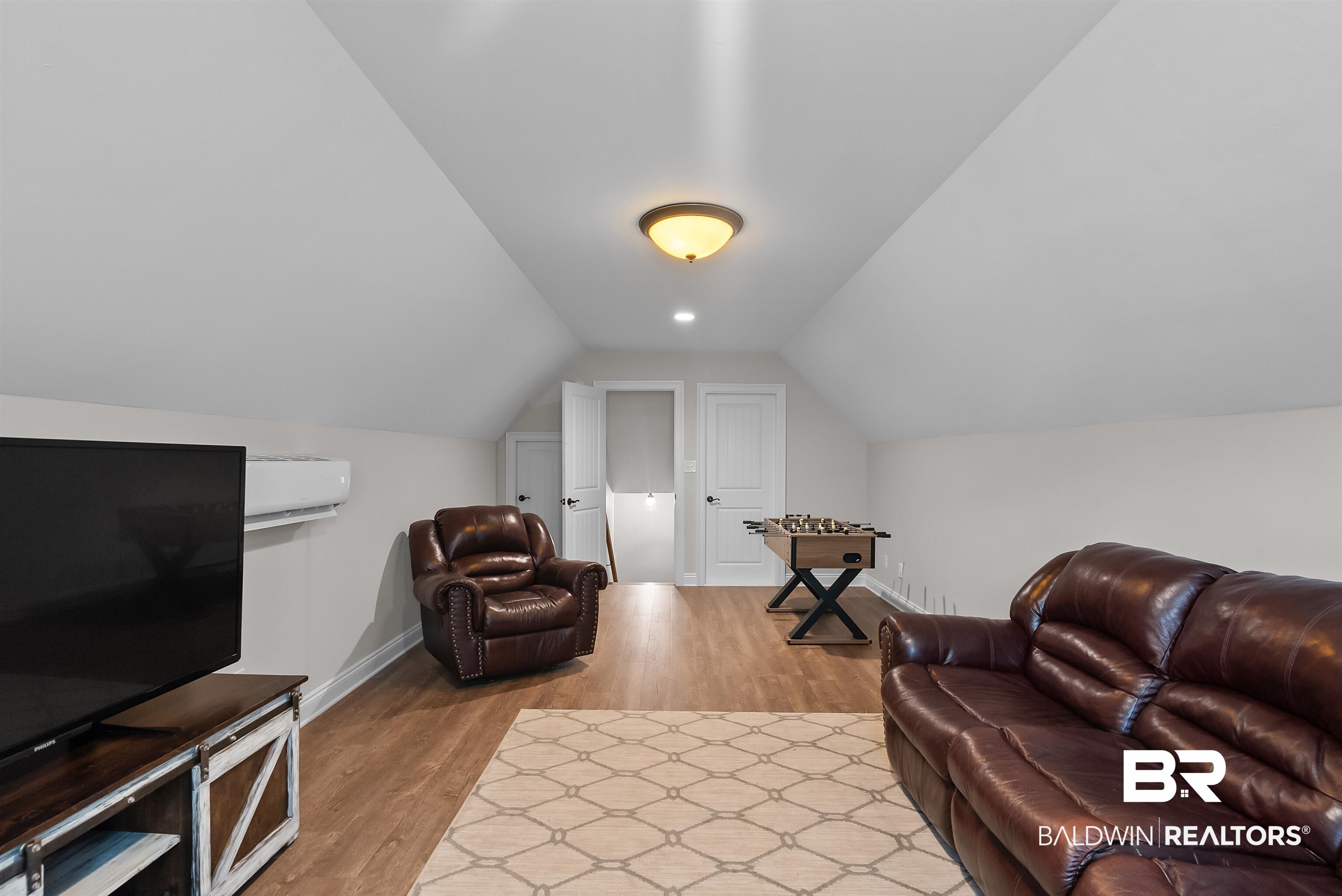 12070 Comalander Road Fairhope, AL 36532 - Photo 39 of 50 Finished bonus room featuring wood-finish flooring, white painted walls, and a vaulted ceiling with a flush-mount light fixture