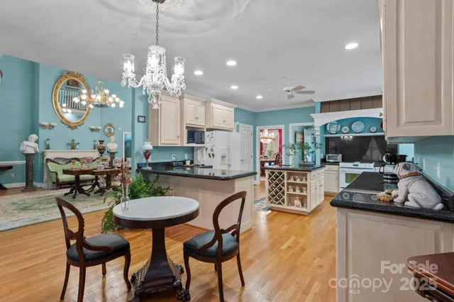 a kitchen with kitchen island granite countertop a sink a stove a dining table and chairs with wooden floor