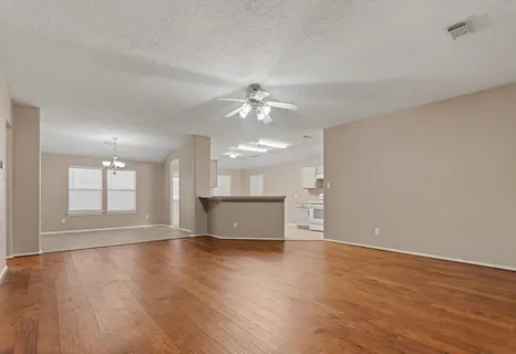 a view of an empty room with window and wooden floor
