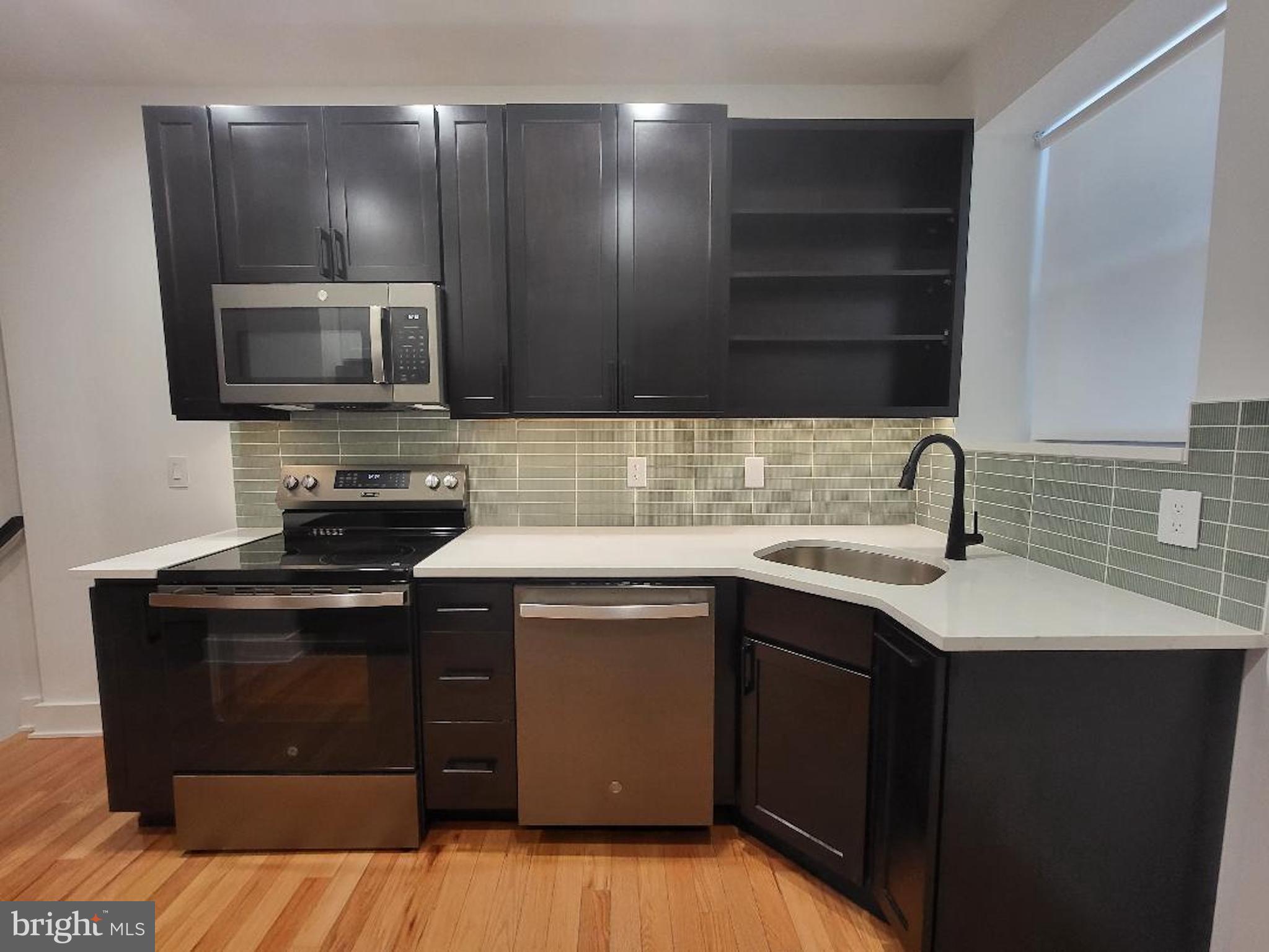1237 South 27th Street Philadelphia, PA 19146 - Photo 10 of 36 a kitchen with a sink and a stove top oven with wooden floor