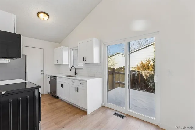 a kitchen with white cabinets and sink