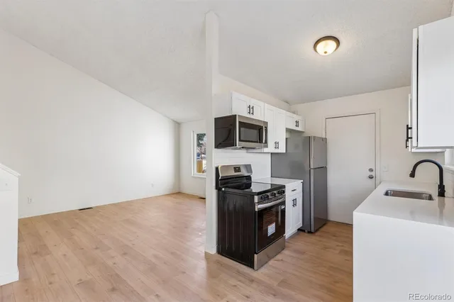 a kitchen with stainless steel appliances a stove top oven a sink and a refrigerator